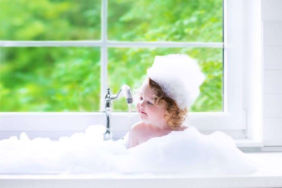 A young child in a bathtub with bubbles.