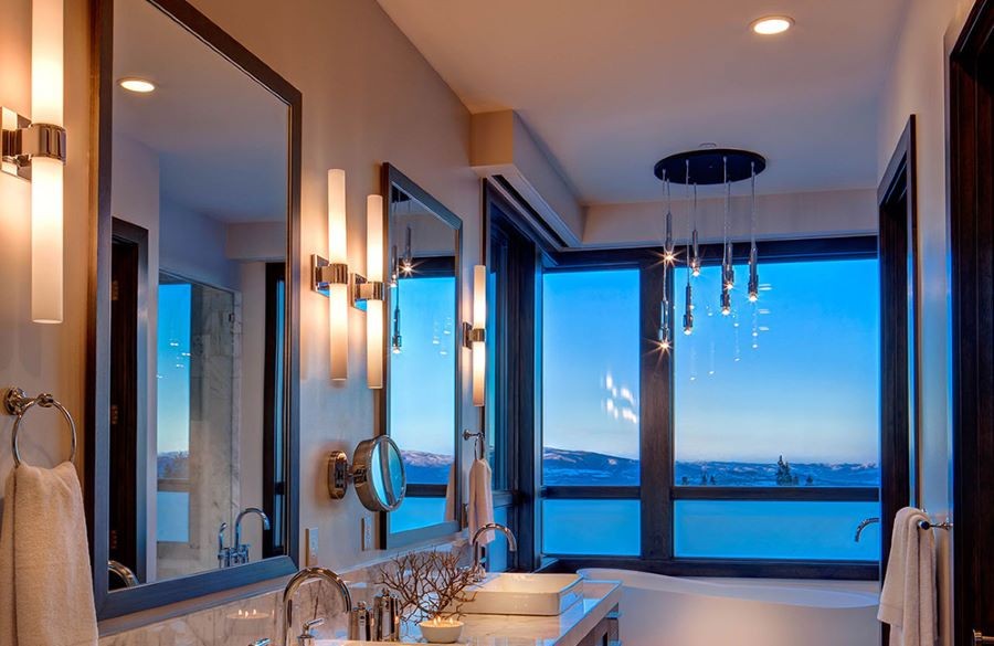 A bathroom with varying light fixtures and a chandelier over the tub.