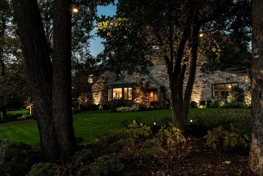 Exterior of a stone house illuminated by outdoor lighting design. 
